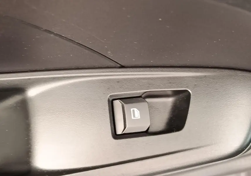 Gros plan sur le bouton de commande de vitre électrique noir dans l’habitacle d’une MG3 gris foncé 2024.