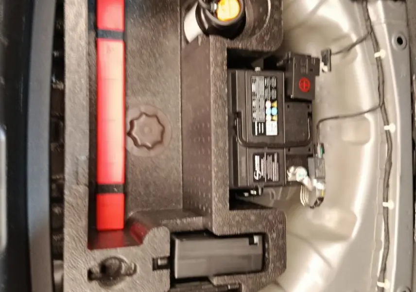 Vue rapprochée du coffre d’un MG3 2024 gris foncé, montrant la batterie et le rangement d’outils intégrés.