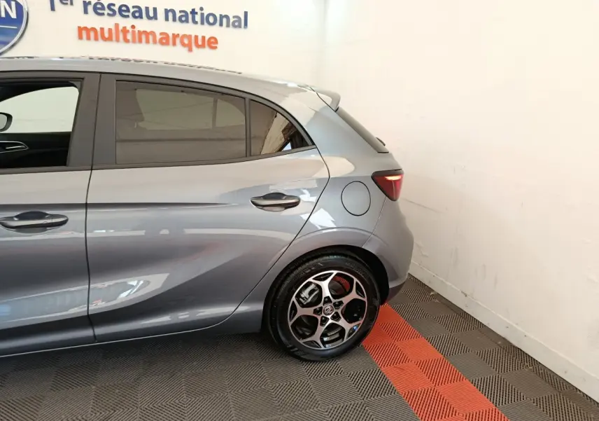 Vue latérale arrière droite d'une MG3 gris foncé avec jante alliage et feu arrière LED visible en intérieur showroom.