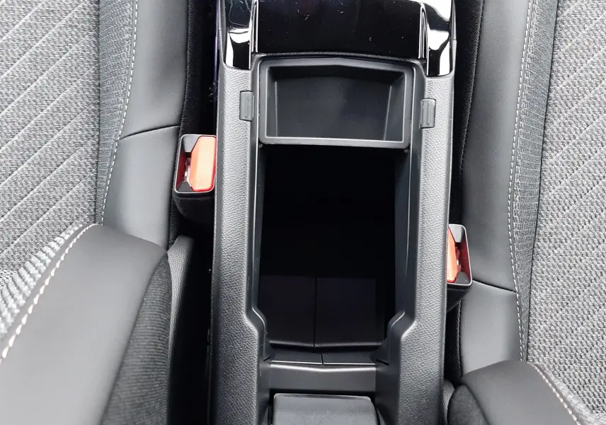 Vue plongeante sur la console centrale noire et les sièges gris tissu du Peugeot 2008 hybride 2025.