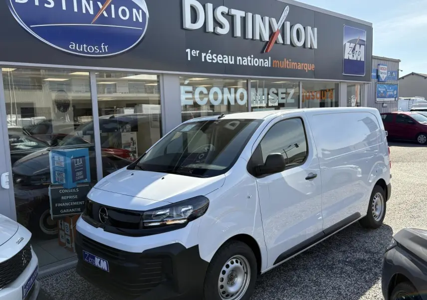 Vue 3/4 avant droite d’un Opel Vivaro blanc 2024 utilitaire avec calandre noire et jantes acier, devant un concessionnaire.