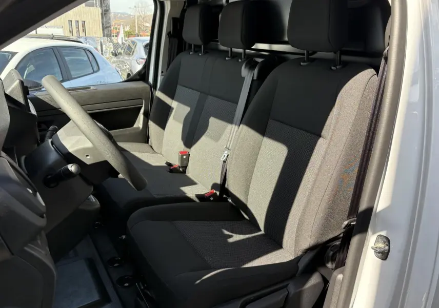 Vue intérieure côté conducteur de l'Opel Vivaro blanc 2024, montrant la banquette avant en tissu bi-ton noir et gris.