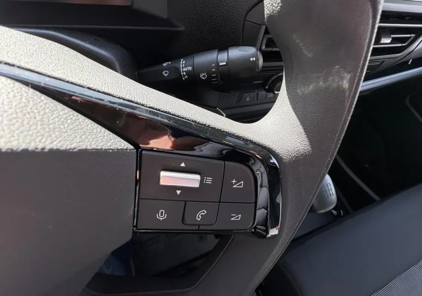 Gros plan sur les commandes au volant et levier de vitesse manuel dans l’habitacle sombre de l’Opel Vivaro blanc.