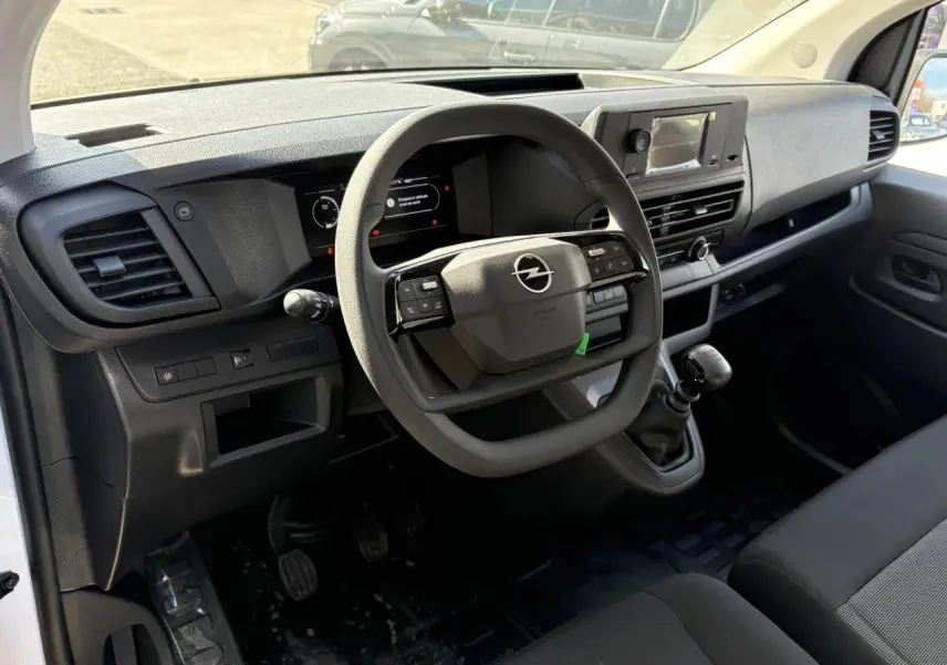Vue intérieure côté conducteur de l'Opel Vivaro 2024, tableau de bord noir avec volant multifonction et boîte manuelle.