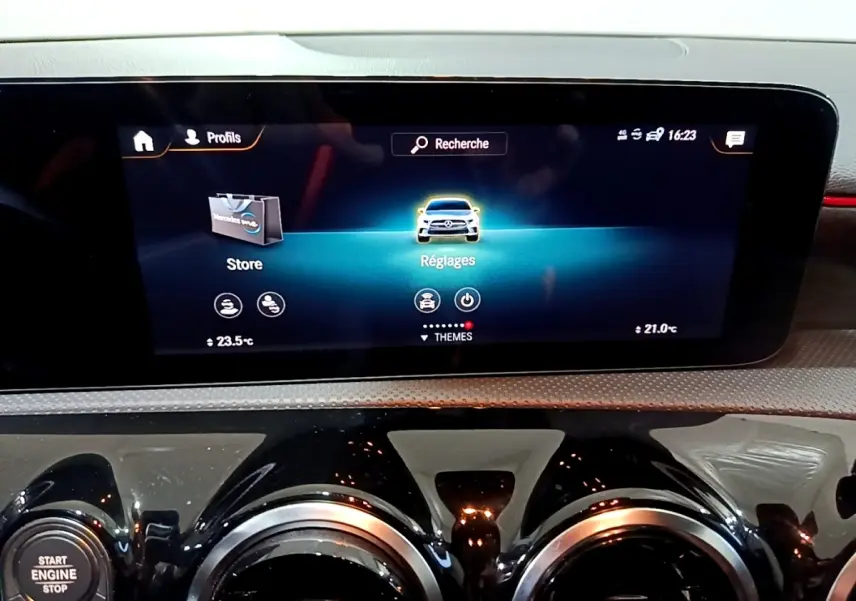 Vue rapprochée de l’écran tactile central et des aérateurs ronds noirs du tableau de bord d’une Mercedes Classe A gris foncé.