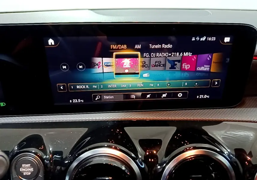 Gros plan sur l’écran tactile central et les aérateurs ronds noirs du tableau de bord de la Mercedes Classe A gris foncé.