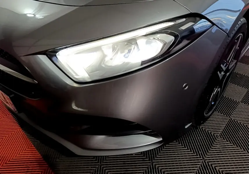 Gros plan sur l'avant droit gris foncé d'une Mercedes Classe A 250 e AMG Line avec phare LED allumé.