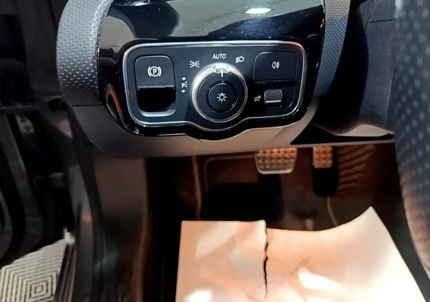 Gros plan sur le panneau de commande des phares et frein à main électrique, intérieur noir du Mercedes Classe A AMG Line.