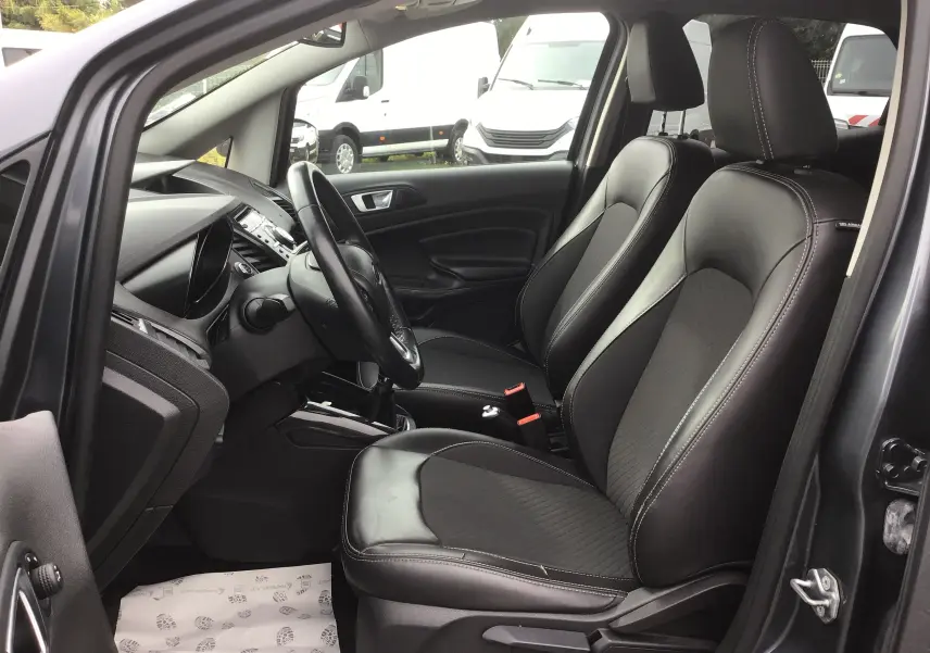 Vue intérieure côté conducteur du Ford EcoSport gris foncé, mettant en valeur les sièges avant en cuir noir et le tableau de bord.