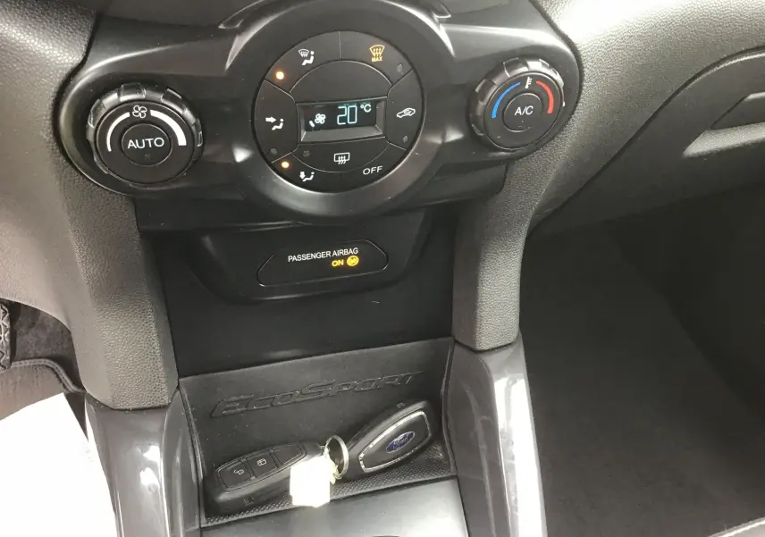 Gros plan sur la console centrale du Ford EcoSport gris foncé, montrant la climatisation digitale et la clé mains libres.