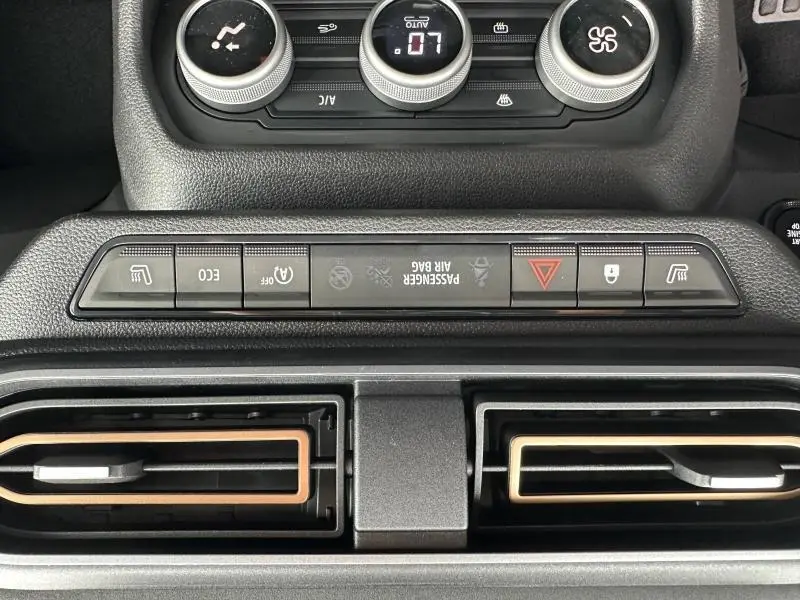 Vue rapprochée du tableau de bord du Dacia Jogger 2024, montrant les commandes de climatisation et les aérateurs avec inserts brun Terracota.