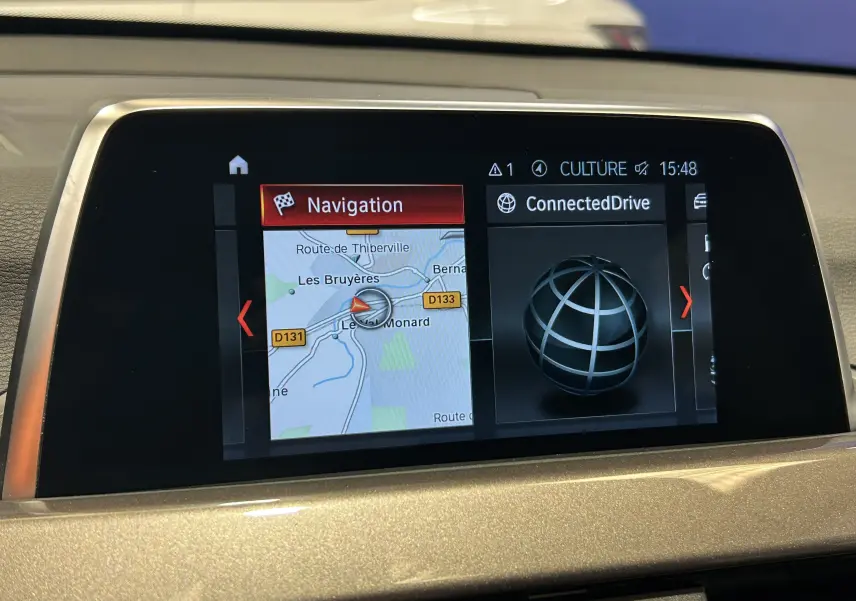 Écran central de navigation et ConnectedDrive du BMW X1 blanc, vue rapprochée de l'interface multimédia.