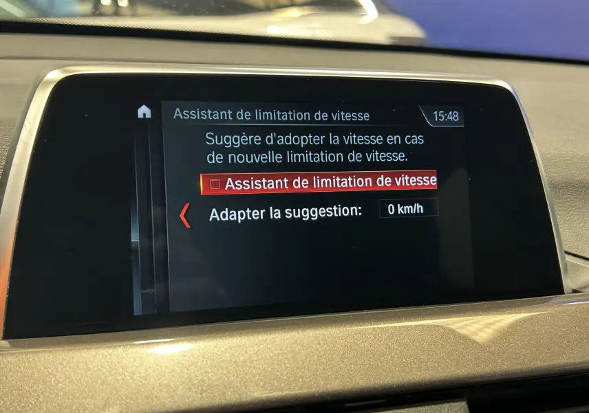 Écran central du BMW X1 blanc 2018 affichant l'assistant de limitation de vitesse avec option à 0 km/h.