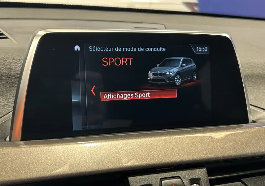 Écran central intérieur montrant le mode de conduite SPORT avec illustration d’un BMW X1 gris en vue 3/4 avant.