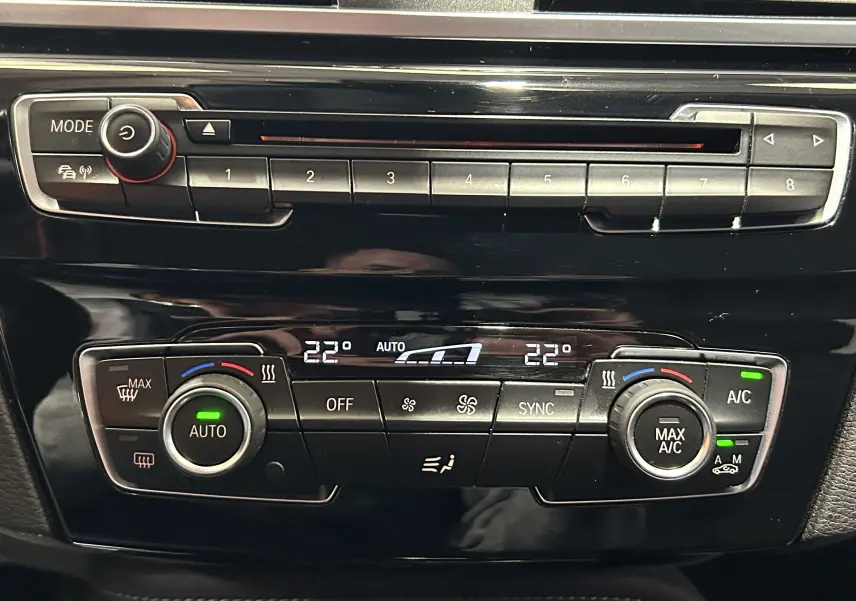 Détail du tableau de bord noir du BMW X1 2018, montrant la climatisation automatique et la radio.