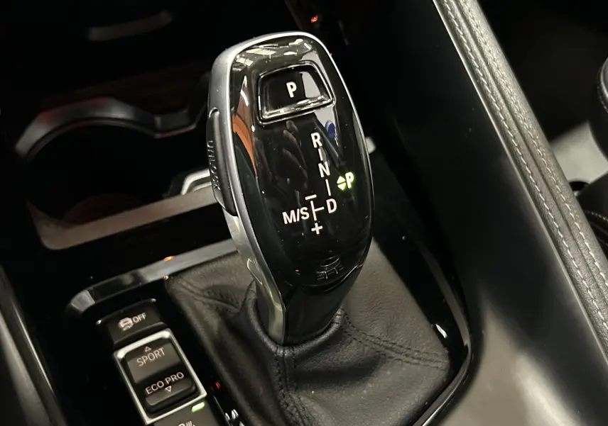 Le levier de vitesses automatique noir brillant de la BMW X1 sDrive18iA, vu en gros plan depuis le dessus.