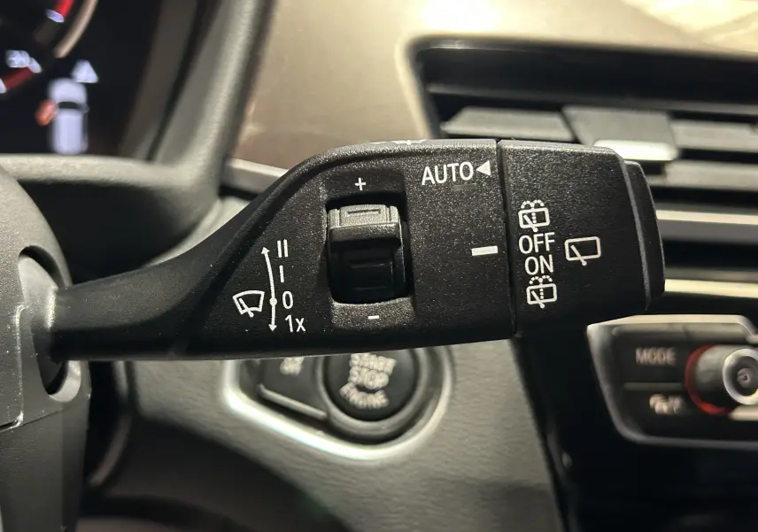 Gros plan sur la commande des essuie-glaces du BMW X1 blanc 2018, avec bouton rotatif et pictogrammes blancs.