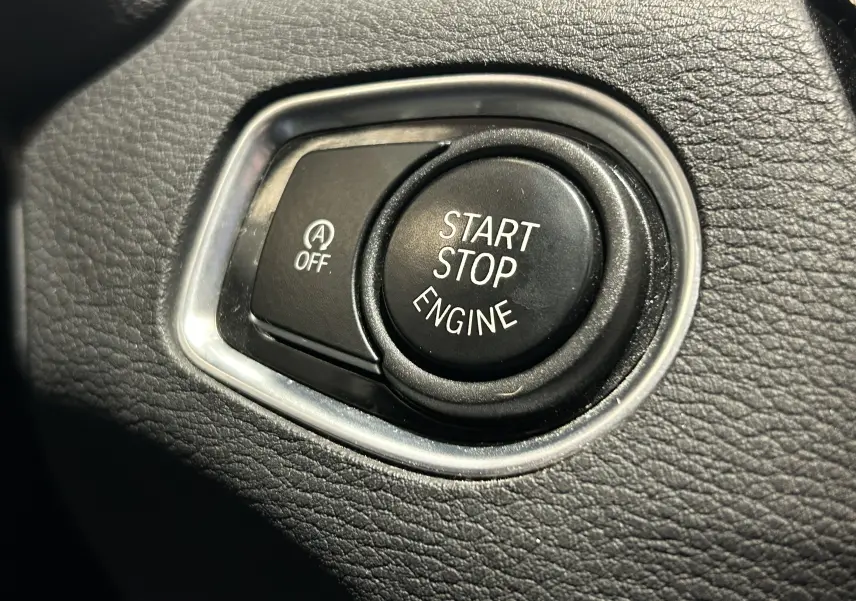 Gros plan sur le bouton Start Stop Engine noir entouré de cuir noir texturé dans une BMW X1 2018.