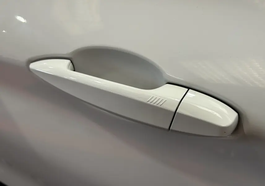 Poignée de porte blanche en gros plan sur une BMW X1 sDrive18iA 2018, finition lisse avec rainures tactiles.
