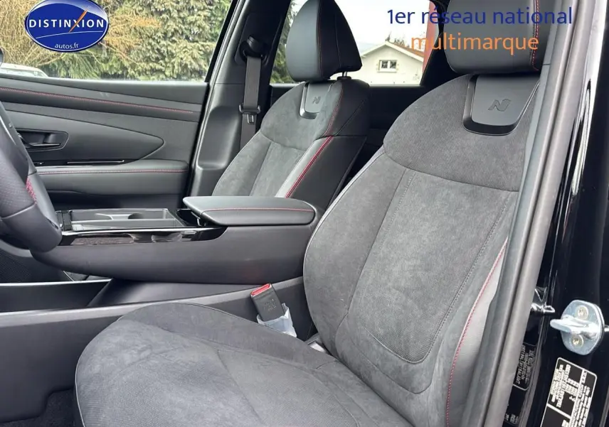 Vue intérieure côté conducteur du Hyundai Tucson 2026 noir, sièges N-line en tissu gris avec surpiqûres rouges.