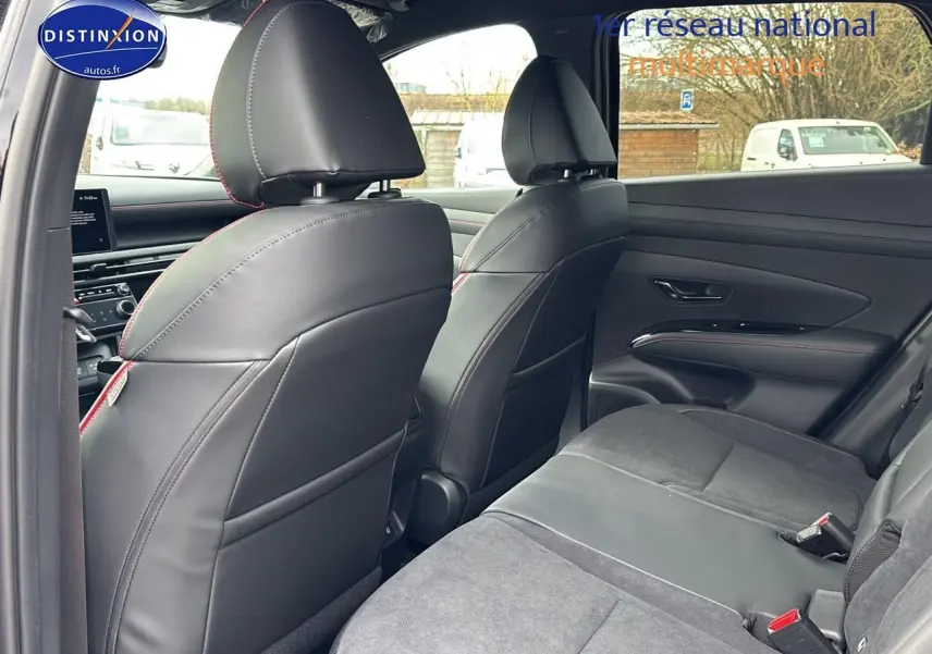 Vue intérieure arrière du Hyundai Tucson 2026 noir, sièges cuir et alcantara avec surpiqûres rouges, ambiance N Line.