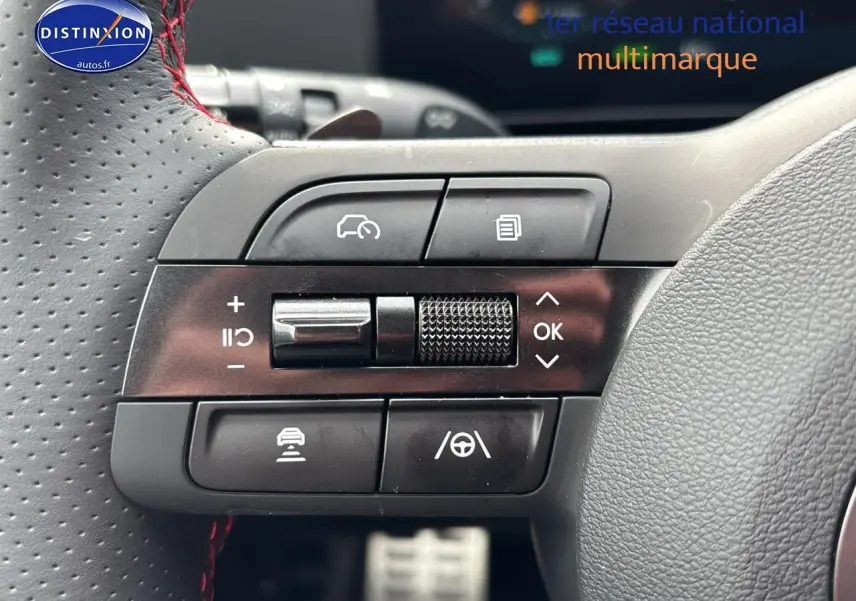 Gros plan sur les commandes multifonctions noires du volant cuir perforé avec surpiqûres rouges du Hyundai Tucson noir.