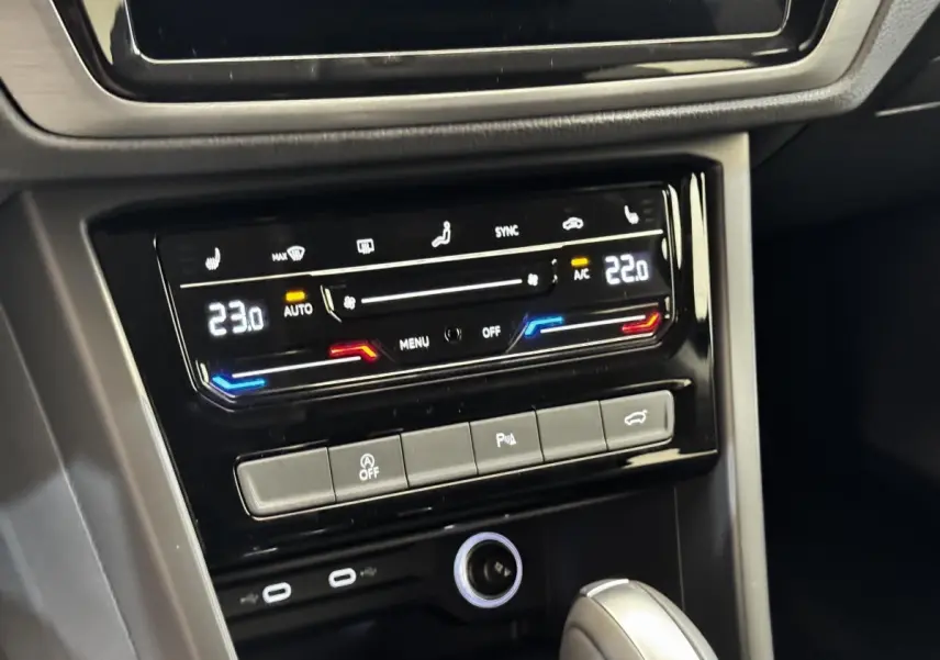 Vue rapprochée du tableau de bord noir du Volkswagen Touran 2024, montrant la climatisation digitale et la console centrale.