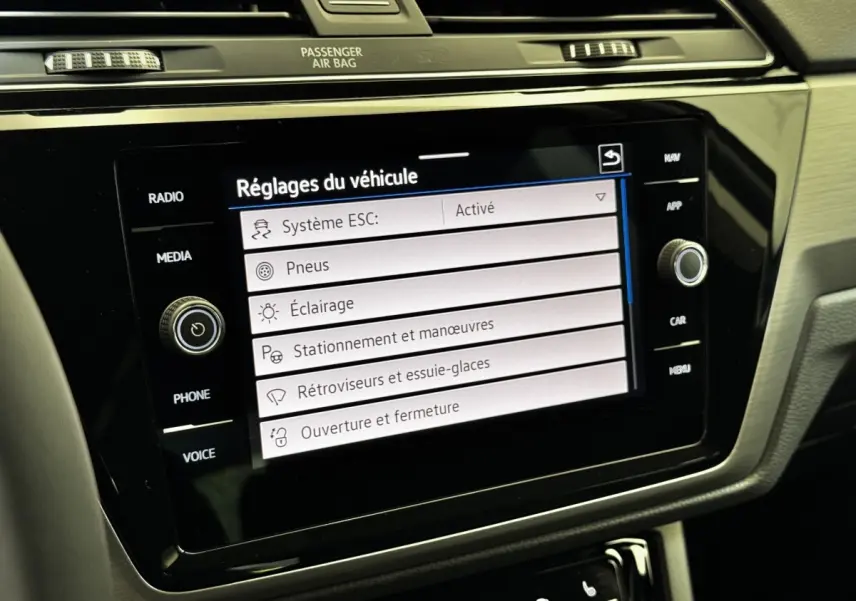 Écran tactile central du tableau de bord du Volkswagen Touran 2024 affichant les réglages du véhicule, intérieur noir.