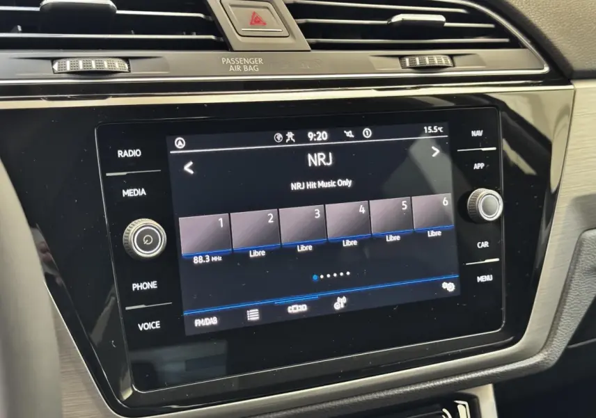 Gros plan sur l’écran tactile central du Volkswagen Touran bleu 2024 affichant la radio NRJ.