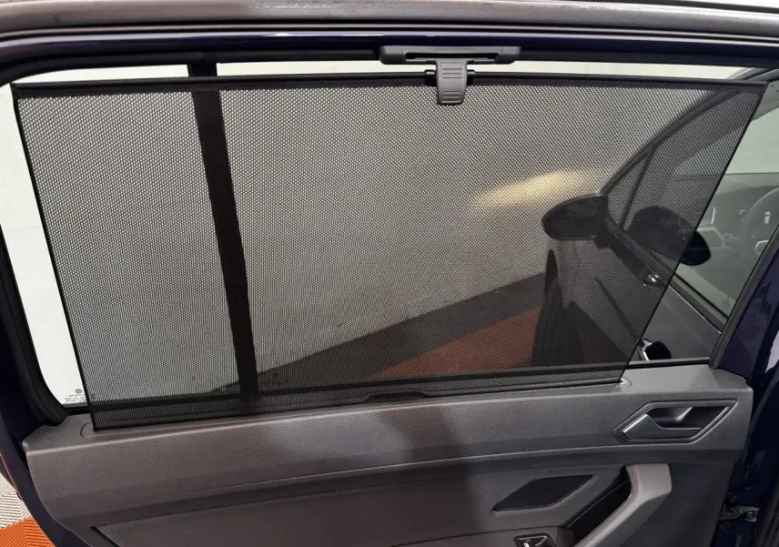Store pare-soleil déployé sur la porte arrière côté gauche d’un Volkswagen Touran bleu 2024.