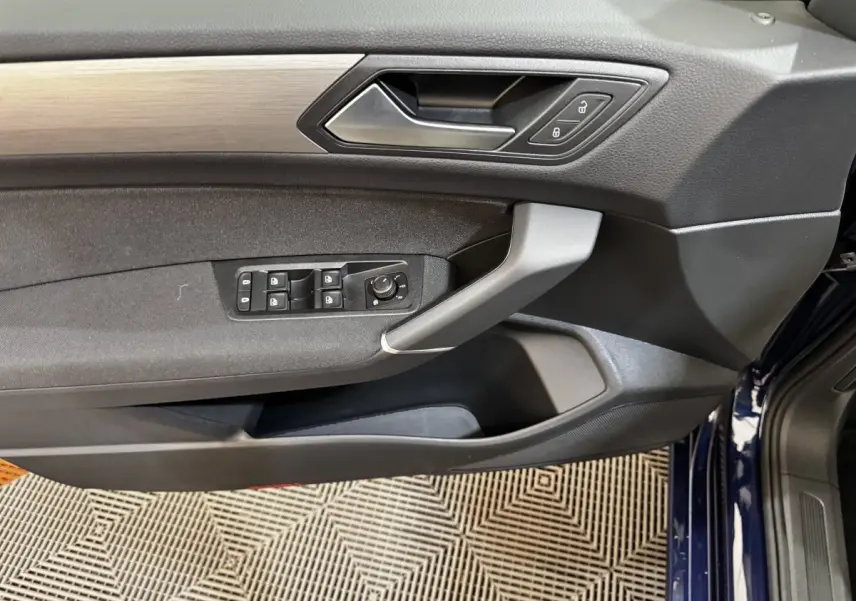 Vue rapprochée de la porte avant gauche du Volkswagen Touran bleu 2024 avec commandes de vitres et verrouillage.