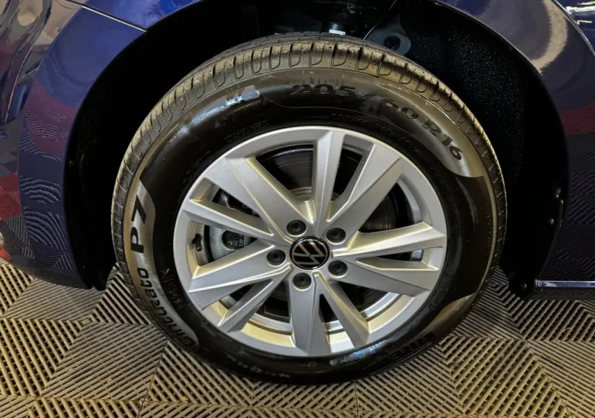 Gros plan sur la roue avant gauche du Volkswagen Touran bleu 2024 avec jante alliage argentée et pneu Pirelli.