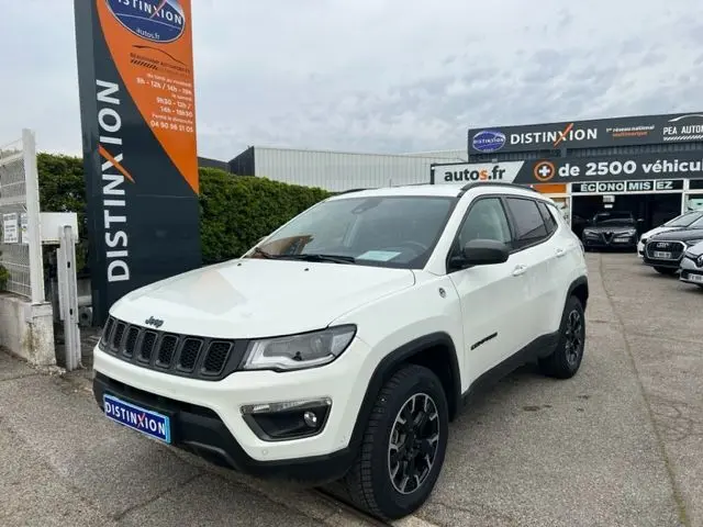 Vue 3/4 avant d'un Jeep Compass blanc hybride rechargeable 2020 avec jantes noires et calandre distinctive.