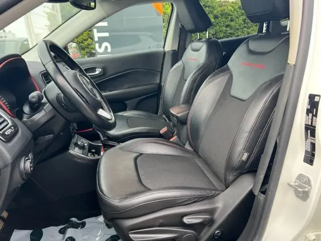Vue intérieure côté conducteur du Jeep Compass blanc 2020, sièges en cuir noir avec surpiqûres rouges et logo Trailhawk.