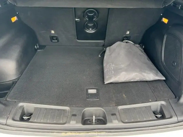 Coffre ouvert du Jeep Compass blanc 2020, vue intérieure montrant un sac gris Jeep posé sur le tapis noir.