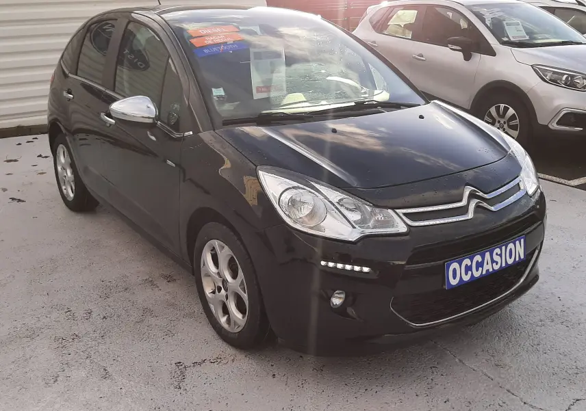 Citroën C3 noire vue en 3/4 avant droit avec feux diurnes LED et plaque "OCCASION" sur parking extérieur.