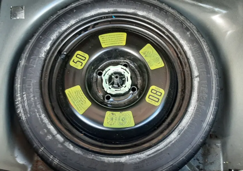 Gros plan sur la roue de secours noire du coffre d'une Citroën C3 BlueHDi 75 Exclusive noire de 2016.