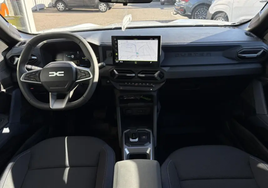 Vue intérieure avant du Dacia Duster 2024, tableau de bord noir avec écran tactile central et volant multifonction.