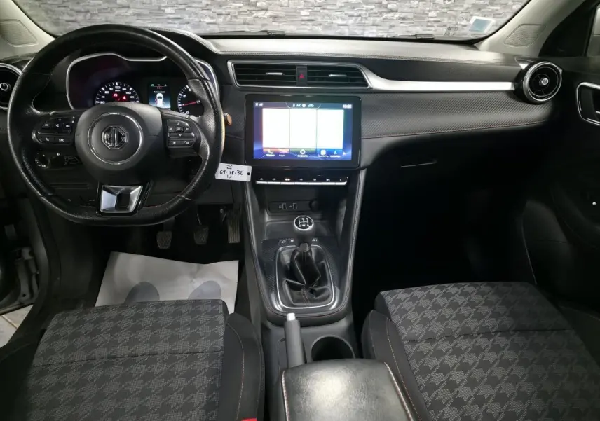 Intérieur avant du MG ZS gris 2023, vue centrée sur le volant cuir, écran tactile et levier de vitesse manuel.
