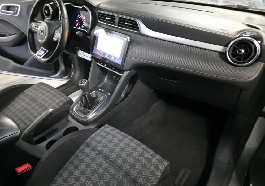 Intérieur côté passager du MG ZS gris 2023, montrant la console centrale avec écran tactile et levier de vitesses manuel.