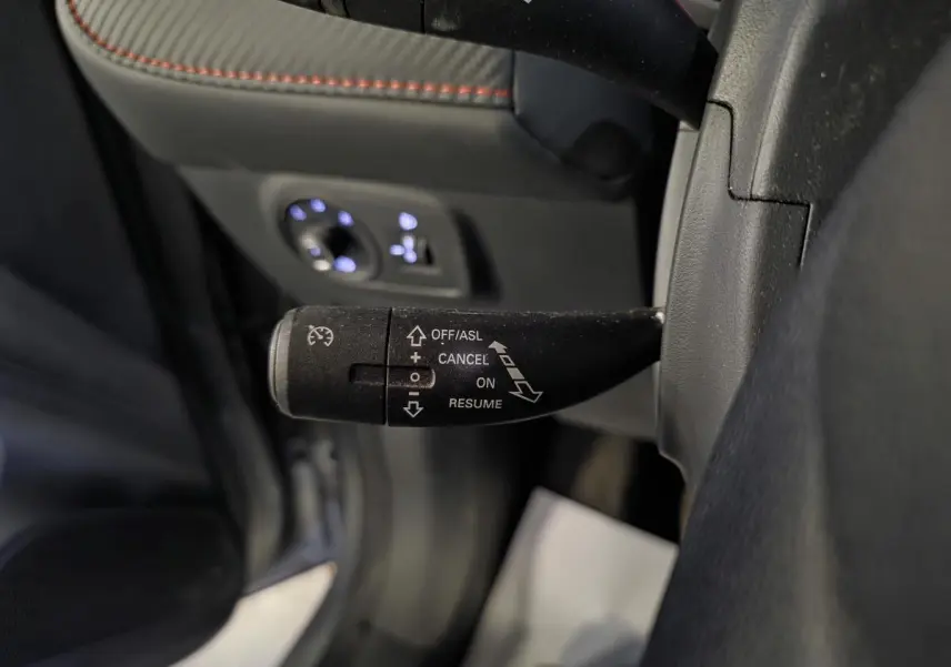 Gros plan sur la manette de régulateur de vitesse côté gauche du volant dans l’habitacle gris du MG ZS 2023.