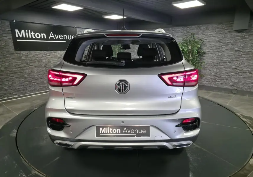 Vue arrière d'un MG ZS gris métallisé 2023 avec feux arrière LED allumés dans un showroom.