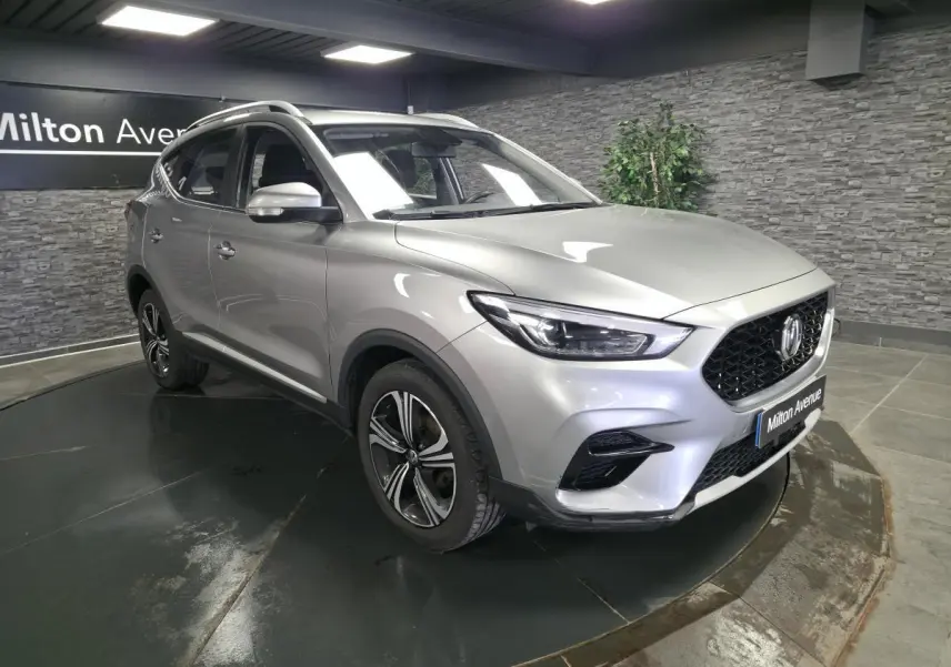 MG ZS gris métallisé vu en 3/4 avant droit, avec jantes alliage noires et calandre noire distinctive.