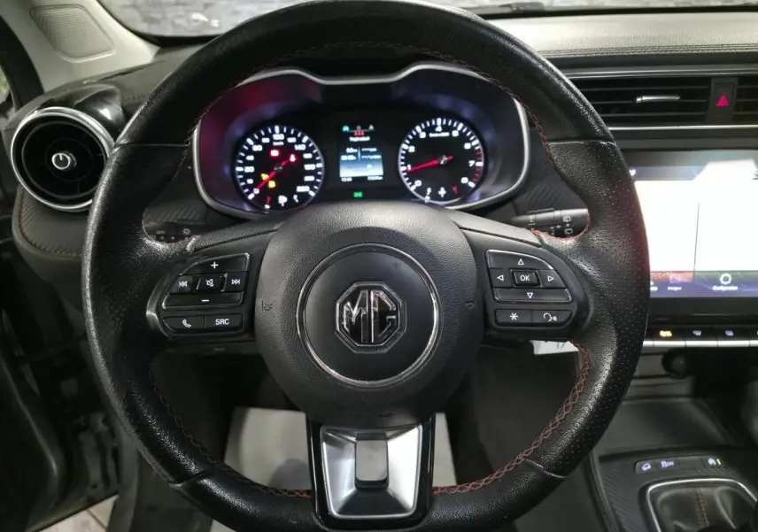 Vue intérieure centrée sur le volant cuir noir du MG ZS 2023 avec commandes intégrées et tableau de bord lumineux.