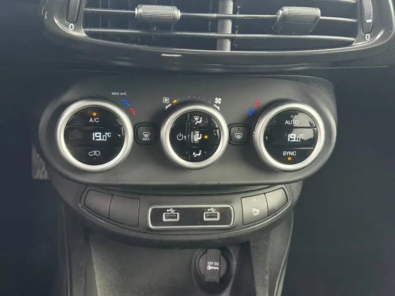 Gros plan sur les commandes de climatisation et les ports USB du tableau de bord du Fiat 500X 2024, finition noire.