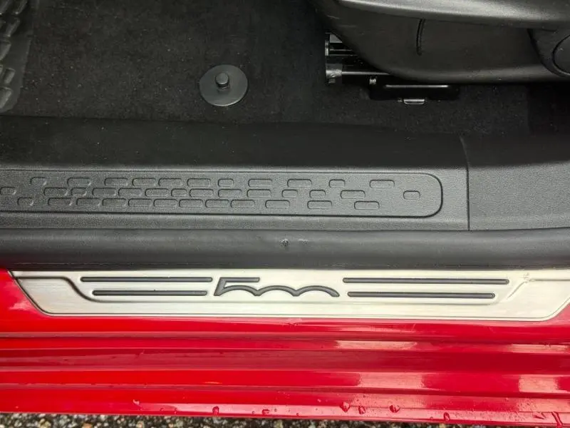 Gros plan sur la plaque de seuil de porte avec logo 500 sur une FIAT 500X rouge Passione pastel, côté gauche.