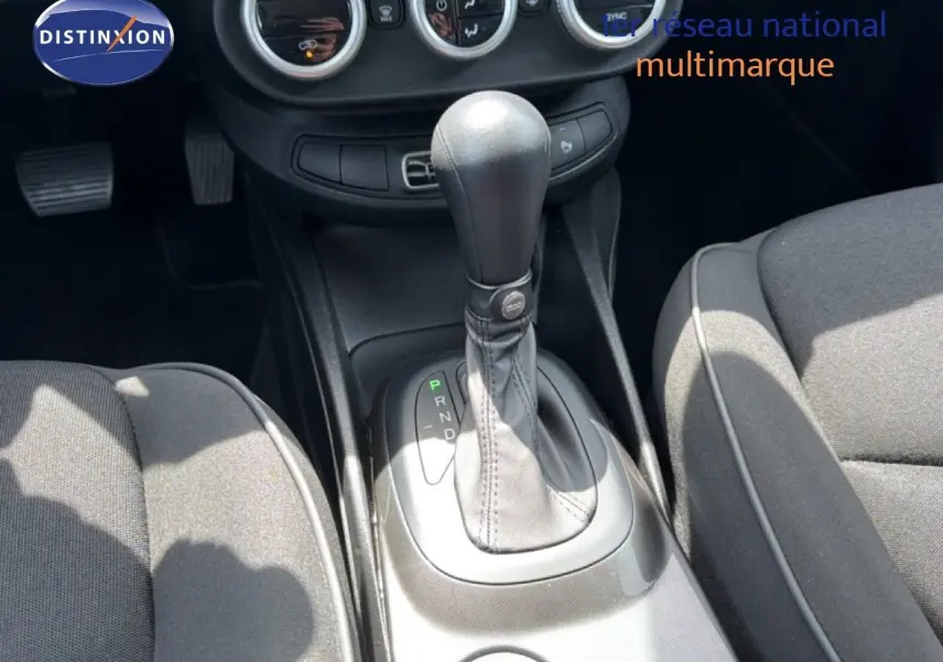 Gros plan sur la console centrale et levier de vitesse automatique d’une Fiat 500X, intérieur tissu gris.