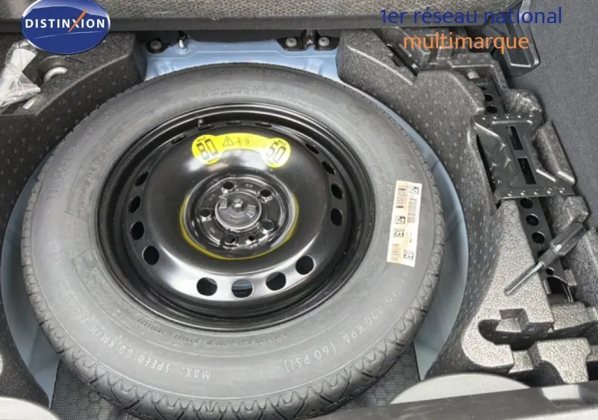 Vue en plongée sur la roue de secours noire dans le coffre d'une FIAT 500X Bleu Venezia 2024.