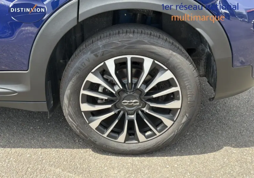 Gros plan sur la roue avant droite d’un FIAT 500X bleu Venezia avec jante alliage bicolore et logo central.