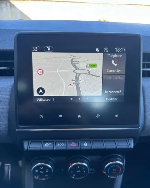 Écran tactile central de la Renault Clio V diesel 2025 montrant la navigation GPS et les commandes de climatisation manuelle.
